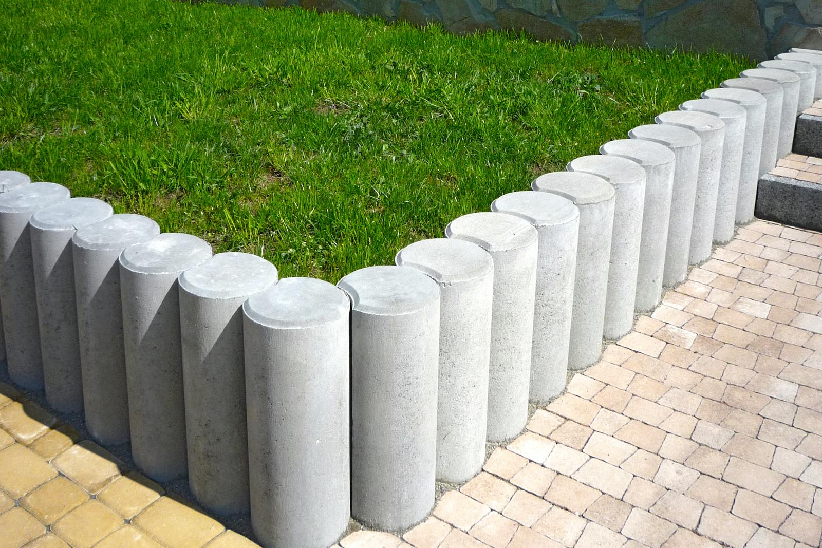 Sharp concrete edge separating a manicured lawn from a mulched bed.